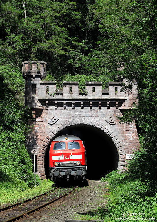 Ab Gerolstein verläuft die Eifelstrecke entlang der Kyll bis Ehrang. Tunnel und Brücken wechseln sich stetig ab. Mit dem RE 12083 verlässt die 218 136 den Friedrich Wilhelmtunnel und wird nach Überqueren der Kyll den Bahnhof Speicher passieren. 17.6.2009