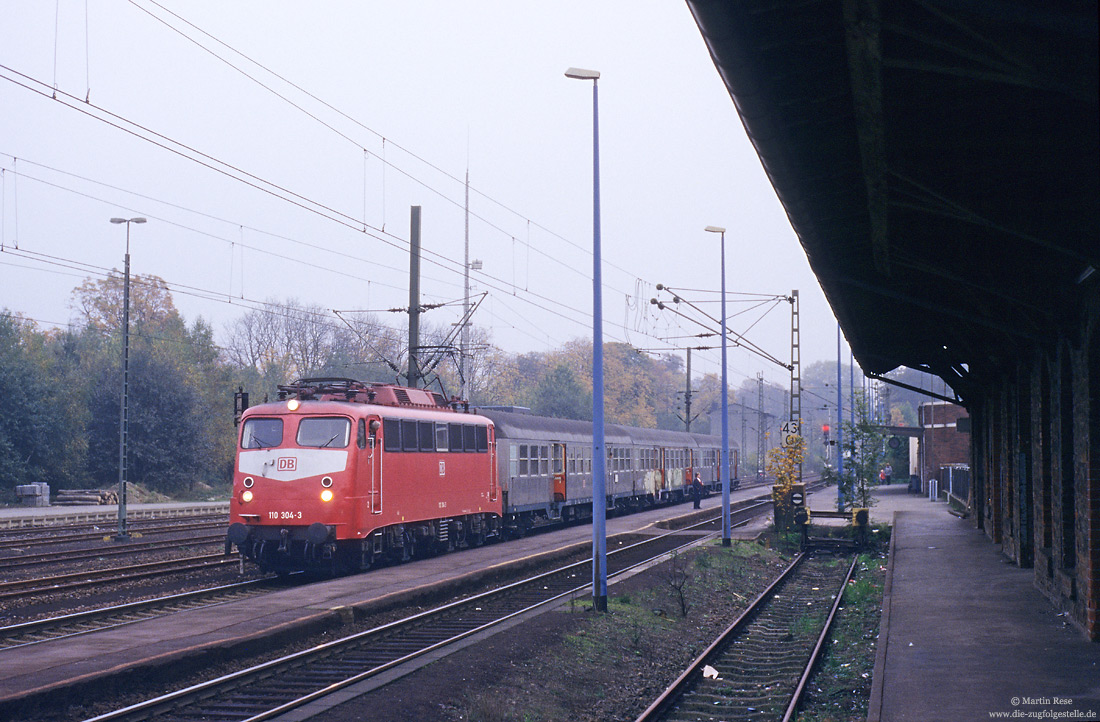 110 304 in Orientrot auf der Siegstrecke im Bahnhof Eitorf