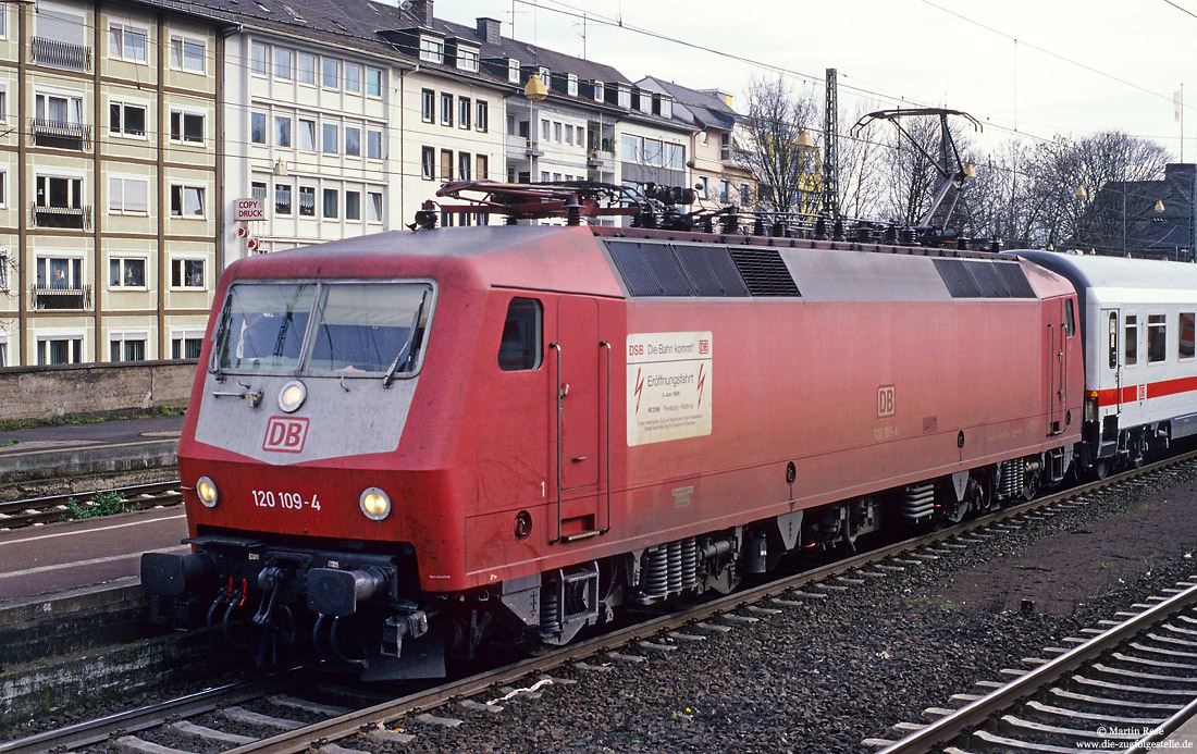 120 109 in Koblenz Hbf mit Aufkleber auf der Seitenwand als Hinweis auf den Eröffnungszug des elektrischen Betriebs zwischen Flensburg und Padborg