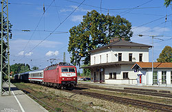 120 117 in Orientrot mit IC im Bahnhof Aßling