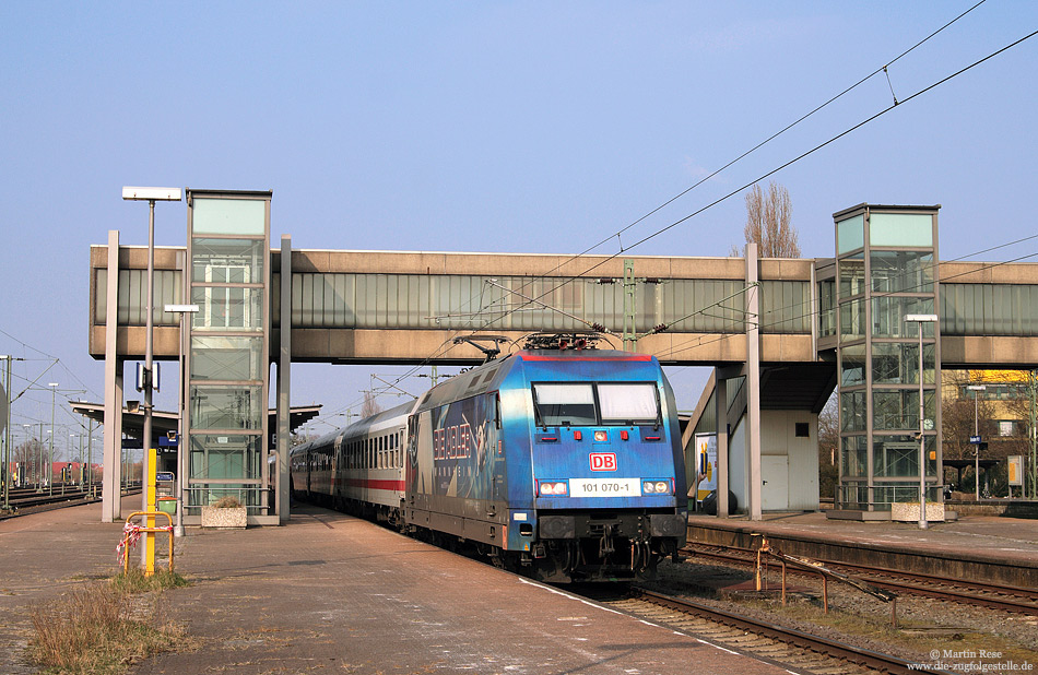 Der heutige Hauptbahnhof von Emden entstand 1971 auf dem Gelände des einstigen Bahnhofs Emden West. Vor der Kulisse der markanten Bahnsteigüberführung fährt die 101 070 mit dem IC130 (Norddeich Mole – Luxemburg) in Emden Hbf ein. 16.3.2011