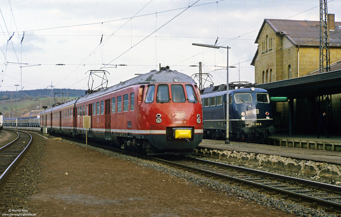 430 411 in Altenbeken Gleis 2, nebenan einfahrende 110 315 in blau