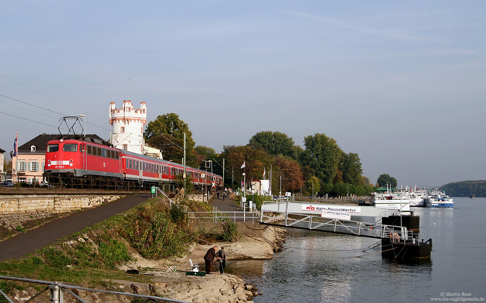 Am 11.10.2007 schiebt die Frankfurter 110 409 die RB 15535 (Assmannshausen - Wiesbaden) durch Rüdesheim, während zwei Angler im Rhein ihre Würmer 