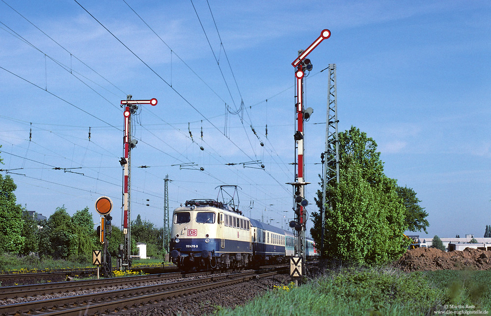 Am südlichen Einfahrsignal von Porz (Rhein) fährt die Dortmunder 110 476 mit dem SE3311 nach Siegen, 8.5.1998. Heute befindet sich an dieser Stelle eine Straßenbrücke über die Strecke, während der Blick auf die Eisenbahn durch Schallschutzwände verdeckt ist.