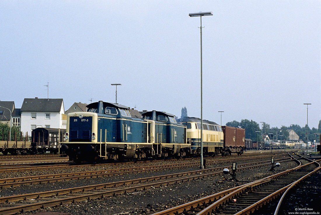  drei Lokomotiven in ozeanblau/beige mit einem Containerwagen im Bahnhof Paderborn Nord Zuglok ist 211 077  