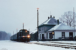 201 216 vom Bw Chemnitz im Schnee im Bahnhof Langenau Sachs mit Bahnhofsgebäude im abendlichem Licht.