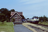 In Stickhausen Velde halten schon seit Ende der 70er Jahre keine Züge mehr. Der Bahnhof wird aber weiterhin für Zugkreuzungen genutzt. Mit dem E1441 (Norddeich Mole - Cottbus) durchfährt die 216 054 den Bahnhof Stickhausen Velde. 29.6.1990