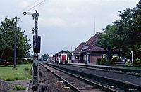 365 838 in orientrot im Bahnhof Ganderkesee mit Empfangsgebäude und Formsignal
